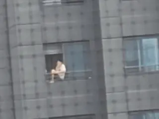 Seorang pria merokok sambil duduk di pagar gedung apartemen lantai 20 menimbulkan kontroversi - Korea Selatan