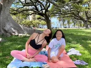 Model SHIHO bermeditasi di rumput dengan legging...putrinya Saran bersamanya