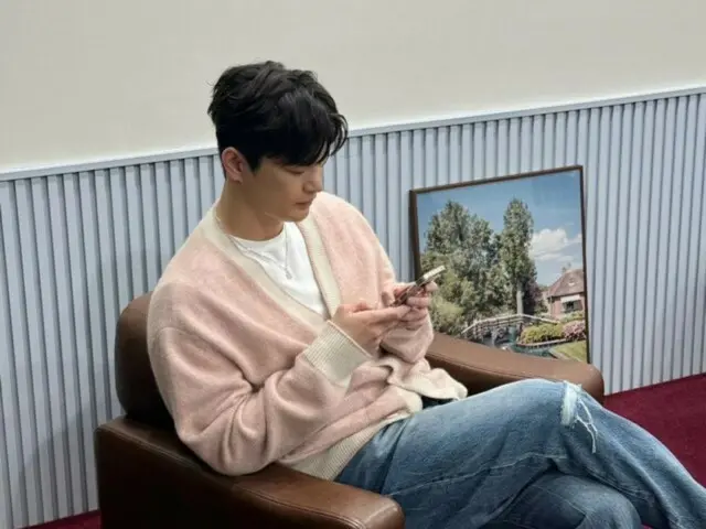 Seo In Guk terlihat santai dengan cardigan berwarna pink... Penasaran apa yang dia lihat di smartphone-nya?