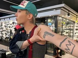 G-DRAGON (BIGBANG) mengunjungi toko senjata dan memamerkan tato senjata di lengannya